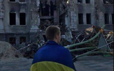Фото дня: хлопець з прапором України біля розбомбленого Драмтеатру у Маріуполі - vogue.ua - місто Маріуполь